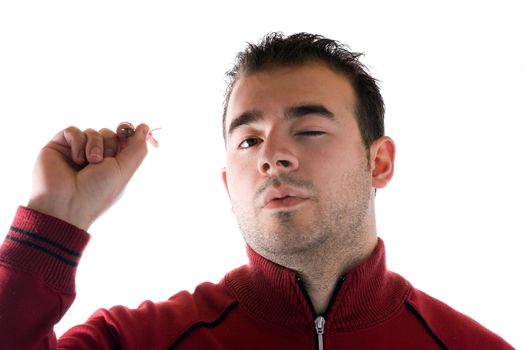 A young man aims a dart as he gets ready to throw it at the target.