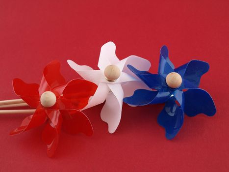 Red, white and blue plastic pin-wheels against a muted red background.