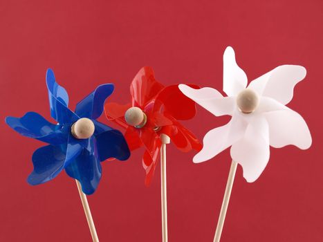 Red, white and blue plastic pin-wheels against a muted red background.