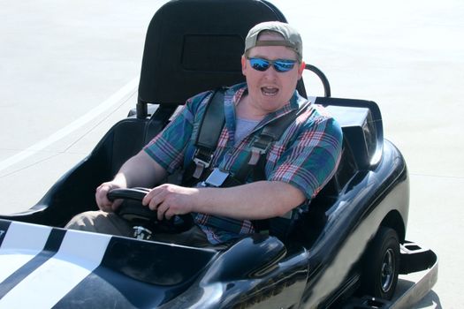 Excited young man riding a go-kart around a track at an amusement park