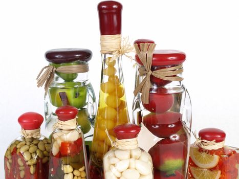 A colorful assortment of pickled spices in different shaped jars on white.