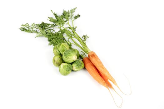 Bunch of ripe crunchy carrots and a pile of green sprouts on a reflective white background