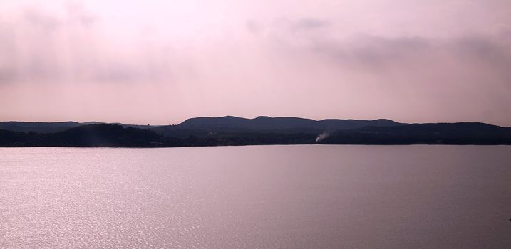 Calm coast of the lake under pink light