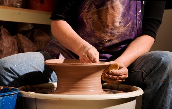 Potter shaping clay on a turning wheel