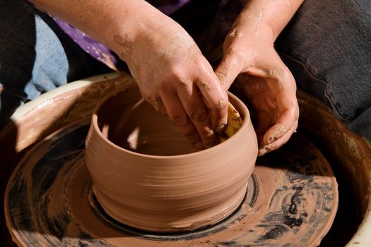 Shaping a new clay pot on a pottery wheel