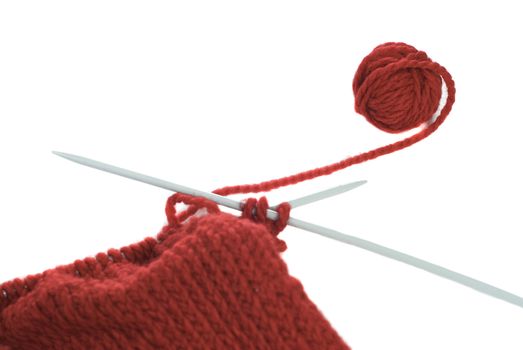 A small ball of yarn being knitted into a cloth, shot on a white background