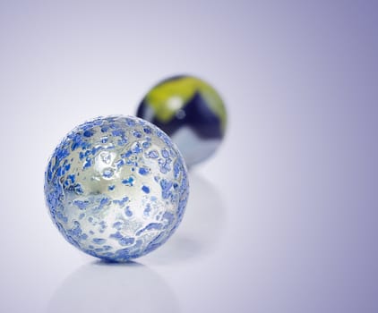 Closeup view of a game of marbles shot on a white background with a slight reflection on the surface