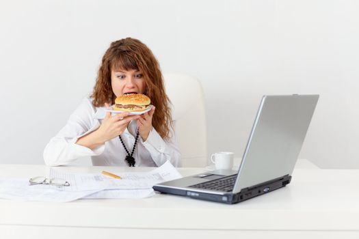 The young girl has hastily dinner a sandwich at office