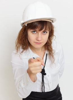 The woman in a protective helmet - the engineer under safety precautions strictly points a finger