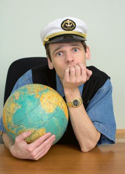 The seaman misses on distant travel sitting at a table with the globe