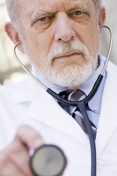 Portrait of an Old Male Doctor with a Stethoscope Pointing to the Camera