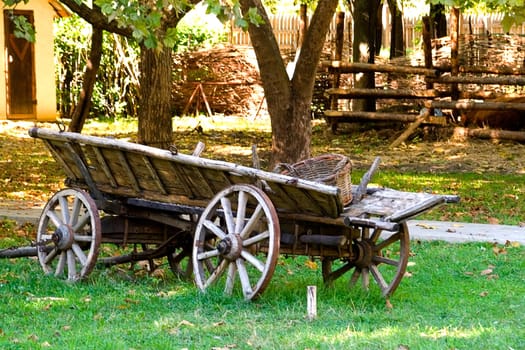 The old cart with a wicker basket stands on a farm 

