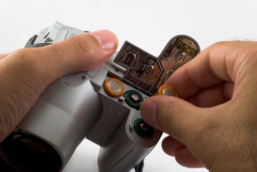 The man inserts a batterys into a digital camera