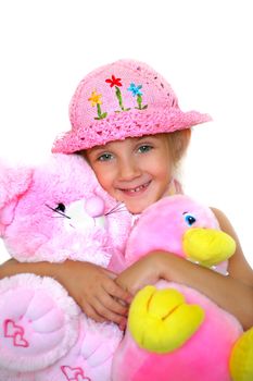 The little girl smiles and embraces soft a toy - duck and a pig.