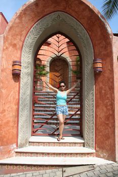 Latin woman in front of gated door
