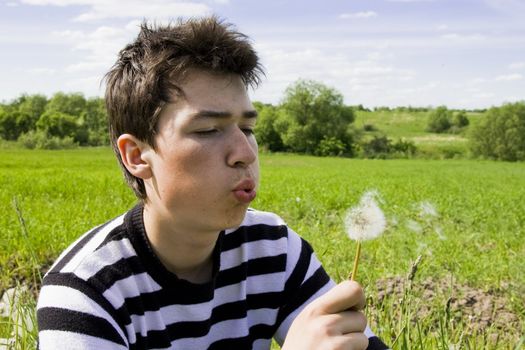 Young teenager blowing dandelion at sunny day