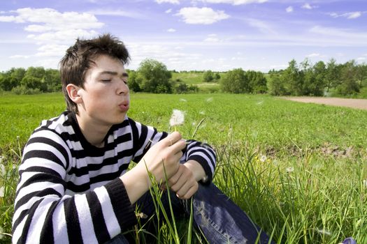 Portrait of teenager blowing a dandelion