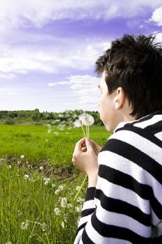 Young teenager blowing dandelion