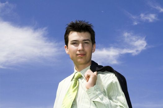 Happy young smiling businessman against cloudy skay background