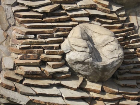 A pile of tiles with large stone in center. Made in Moscow zoo