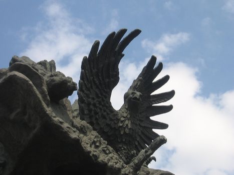 Stone eagle statue in Moscow zoo on a background of the blue sky with clouds