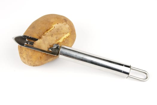 Small brown raw potato with chrome peeler on a reflective white background