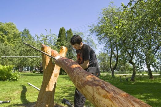 Young man in a garden does a balance swing