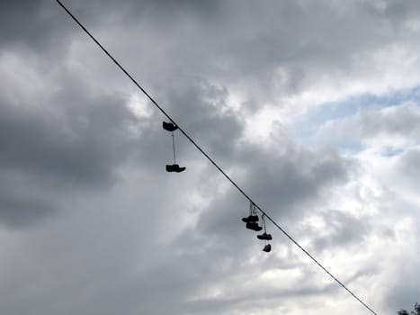 Cute boots are on a wire on a background of sky with clouds
