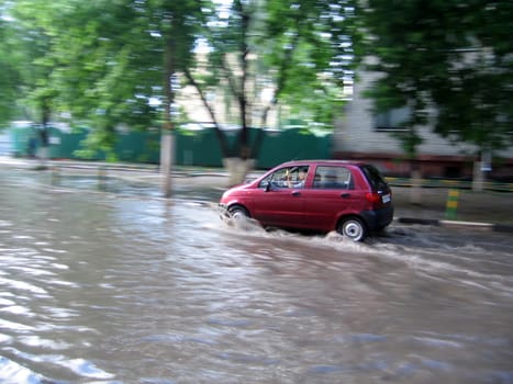 Small red car moves at the water street