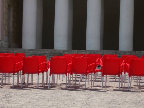 Red plastic chairs near a stage before a concert