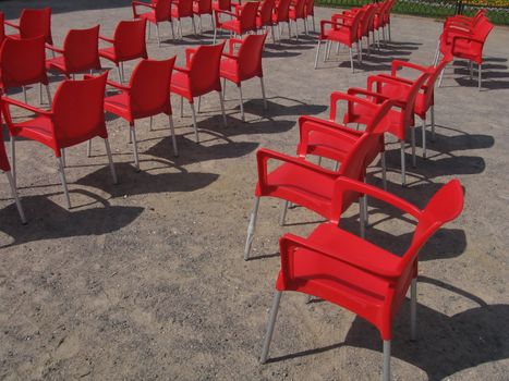 Red plastic chairs on sand before a concert