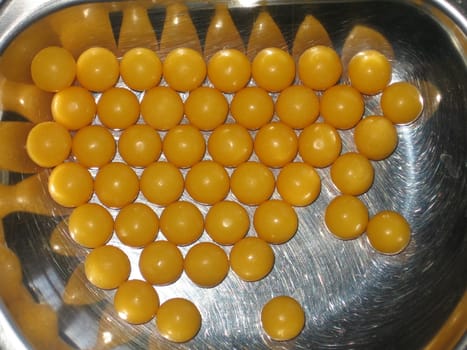 Yellow round vitamin tablets on a metal plate