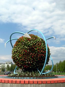 Unusual public spherical flowerbed on a background of blue sky with clouds