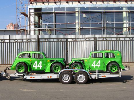 Two green racing cars at the trailer