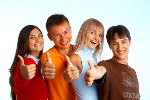 Four young people on white background laughing and giving the thumbs-up sign. 
