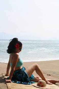 Young Latin woman sitting on beach