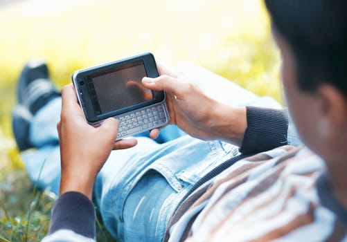 Young man with his pocket computer on a green grass