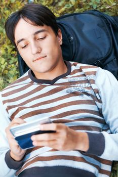 Young man with his PDA on a green grass