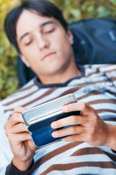 Young man with his PDA on a green grass