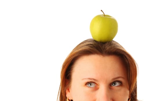 Cropped image of a young attractive woman with a juicy green apple on her head, isolated over white background