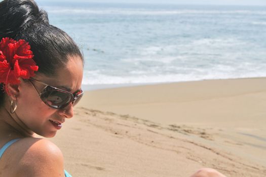 Young Latin woman sitting on beach