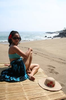 Young Latin woman sitting on beach