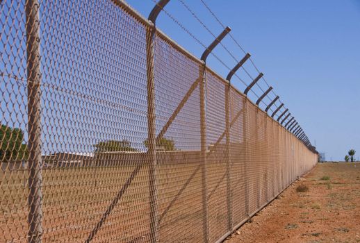 A long nasty fence in the red dirt of Western Australia protects a military base in the desert.