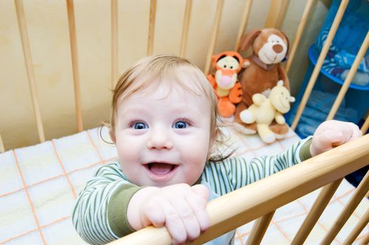 Funny face of baby boy playing in bed