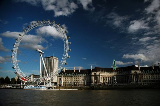 london eye with river, dark blue sky and white clouds