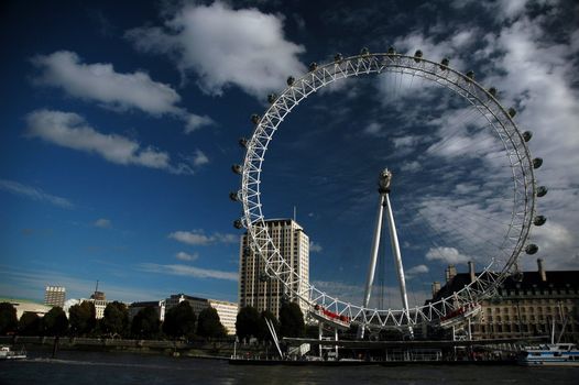 london eye with river, dark blue sky and white clouds