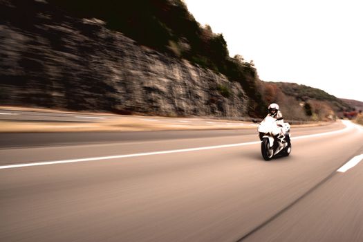 Abstract blur of a pretty girl driving a motorcycle at highway speeds in sepia tone.