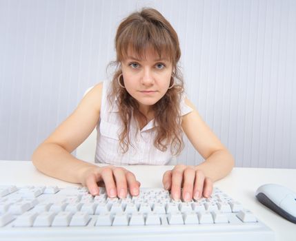 The comical woman sits in front of the monitor with the keyboard