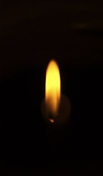 Golden candle flame against black background