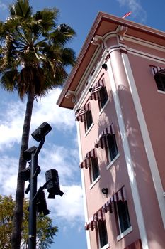 Typical Hollywood building: pink, with palm trees and a blue sky, taken from below and looking up